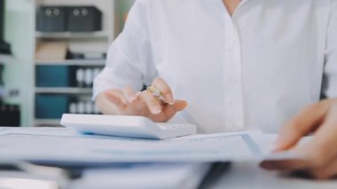 Yakın plan - beyaz bir kalem ve tahta bir masaüstünde bir kalem tutan kadın eli.