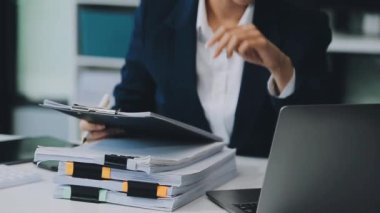 Ofiste belgelerle çalışan genç iş kadını.