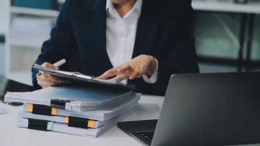 Ofiste çalışırken elinde kalem ve belgeler tutan iş kadını