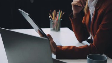 Modern bir ofiste dizüstü bilgisayar kullanan genç bir kadın.