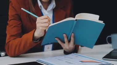 Genç bir kadın kütüphanede kitap okuyor ve okuyor.