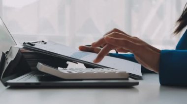 Genç kadın ofiste dizüstü bilgisayar kullanıyor.