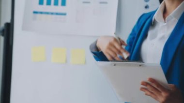 Takım elbiseli genç kadın notlar yazıyor ve modern ofiste çalışıyor.