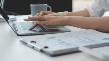 İş ekibi dizüstü bilgisayar ve mali rapor üzerinde çalışıyor.