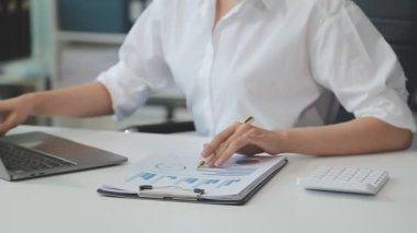 Bilgisayarla çalışan iş kadını ve ofis masasında belgeler.