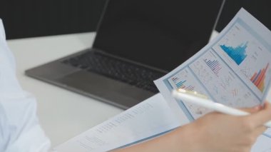 İş kadınlarının elleri bilgisayarda elinde mali raporla kalem tutarken..