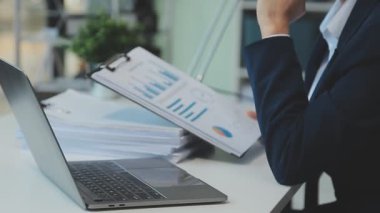 İş adamı mali raporu analiz ediyor ve laptop kullanıyor