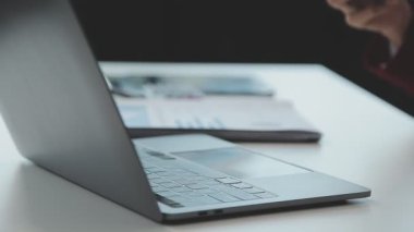 Kadın eli tablet üzerinde çalışıyor. Masasında da defter var.