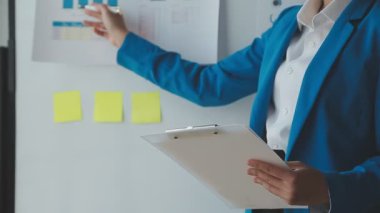 Takım elbiseli genç bir iş kadını elinde bir işaret tutuyor..