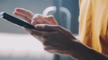 Pencerenin arka planında telefon kullanan bir adam..