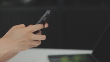 Ofisinde elinde akıllı telefon tutan bir kadın.