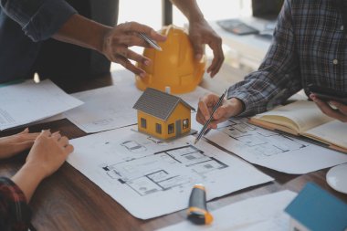 A team of construction engineers talks to managers and construction workers at the construction site. Quality inspection, work plan, home and industrial building design project