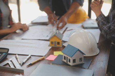 A team of construction engineers talks to managers and construction workers at the construction site. Quality inspection, work plan, home and industrial building design project