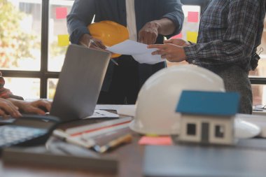 A team of construction engineers talks to managers and construction workers at the construction site. Quality inspection, work plan, home and industrial building design project