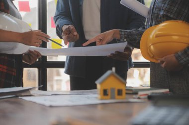 A team of construction engineers talks to managers and construction workers at the construction site. Quality inspection, work plan, home and industrial building design project