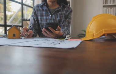 A team of construction engineers talks to managers and construction workers at the construction site. Quality inspection, work plan, home and industrial building design project