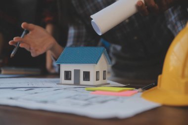 A team of construction engineers talks to managers and construction workers at the construction site. Quality inspection, work plan, home and industrial building design project
