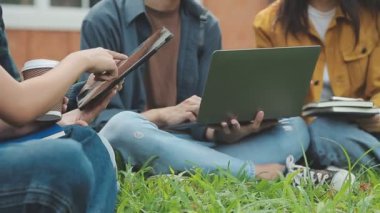 Asyalı genç öğrenciler parkta tablet kullanıyorlar..