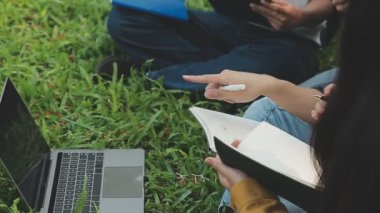 Genç Asyalı adam bahçede dizüstü bilgisayar kullanıyor..
