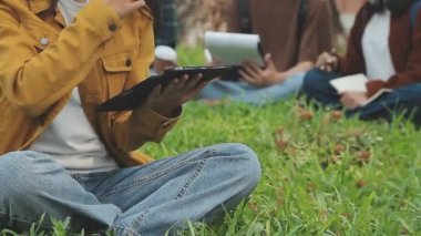 Genç Asyalı kadın parkta tablet bilgisayar kullanıyor. Gençler teknoloji ve sosyal medya kavramını, modern yaşam tarzını kullanıyor.
