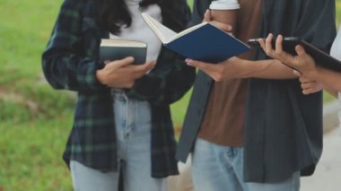 Genç Asyalı öğrenciler kitap okuyor ve parkta oturuyorlar..