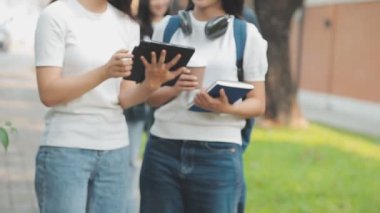 İki Asyalı üniversite öğrencisi dışarıda dizüstü bilgisayarla çalışıyor..