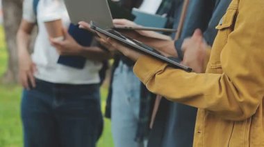 Genç Asyalı öğrenci parkta tablet bilgisayar kullanıyor.