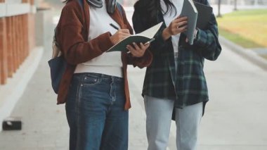 Ellerinde not defterleri olan iki Asyalı öğrenci.