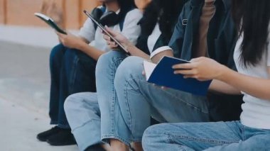 Genç kadınlar yerde oturup kitap okuyorlar..