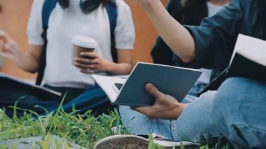 Parkta otururken tablet bilgisayar kullanan gençler.