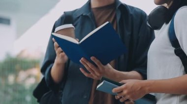 Genç Asyalı öğrenci kampüste kitap okuyor.