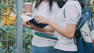 Genç Asyalı kadınlar bir kitap tutuyor ve okuyorlar..
