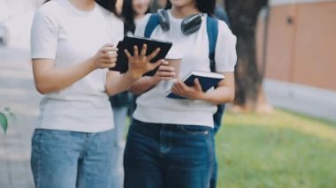 İki genç kız birlikte çalışıyorlar ve ellerinde defterler var. Bir kitap tutuyorlar.