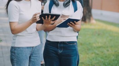 Asyalı iki genç öğrenci parkta birlikte kitap okuyor ve okuyorlar.