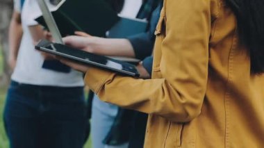Kapalı alanda yürürken elinde kitap tutan ve kameraya bakan öğrencilerin görüntüsü