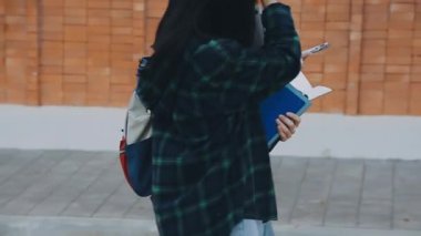 Beyaz gömlekli, kot pantolonlu ve sırt çantalı genç bir kadın.