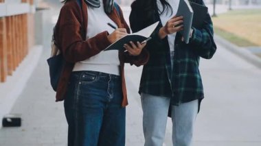 Kitaplar ve tabletlerle günlük kıyafet giymiş iki öğrenci.