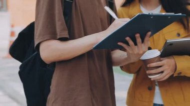 İki genç öğrenci sokakta merdivenlerde otururken dijital tablet kullanıyor.