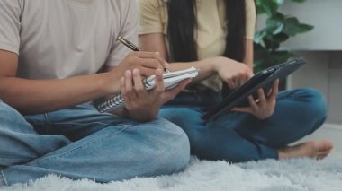 Asyalı erkek ve kadın evde birlikte çalışırken bir tablet yazıyorlar.