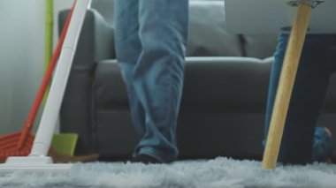 Adam oturma odasını temizliyor.