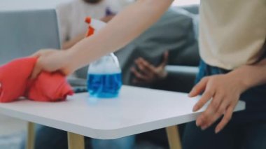 Genç bir kadın dizüstü bilgisayarla masayı temizliyor..