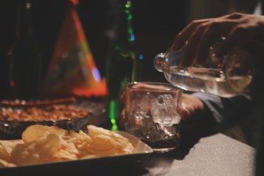 Kutlama gecesi, bardağa viski dök. Kutlamaya gelen arkadaşlarına ver.