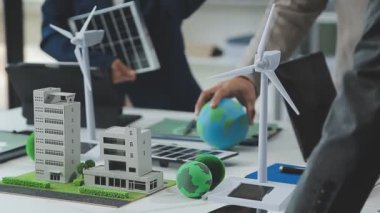 Ofisinde rüzgar türbinleri modeli olan yeşil takım elbiseli bir işadamı..