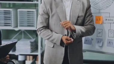 Modern ofiste sunum sırasında iş planlarını meslektaşlarına gösteren iş adamı.