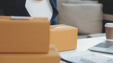 İş kadını paket kutusuyla dizüstü bilgisayarda çalışıyor. çevrimiçi dağıtım kavramı