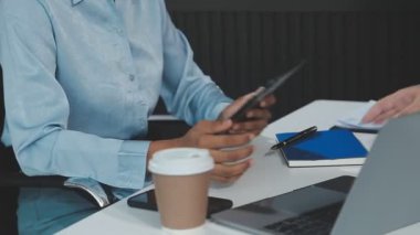 İş kadını elinde tabletle ofiste otururken akıllı telefon kullanıyor..