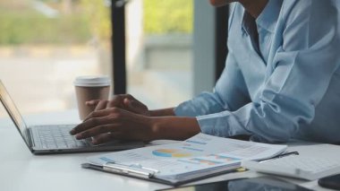 Finans çizelgeleri ve dizüstü bilgisayarla çalışan genç iş kadınlarını kapatın..