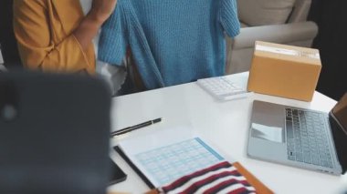 Kadın paketini tutuyor ve ofiste dizüstü bilgisayar kullanıyor.