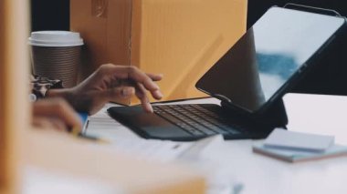 Genç adam ofiste dizüstü bilgisayarını kahve fincanı ve akıllı telefonla kullanıyor.