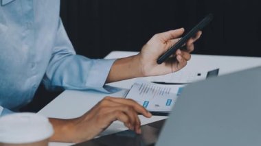 Modern ofis odasında akıllı telefon kullanan genç bir iş adamı.